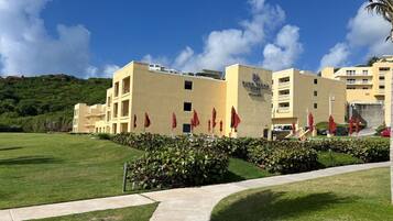 A hotel with a flat roof, multiple floors, and a well-maintained lawn.