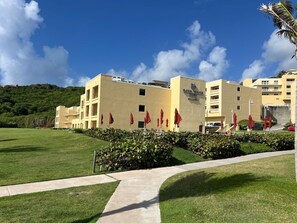 Ein Hotel mit flachem Dach, mehreren Etagen und einem gepflegten Rasen.