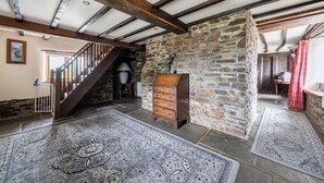 A rustic interior with exposed beams, a stone wall, a wooden staircase, and a traditional wooden dresser. - 16th Century Devon Farmhouse, Stunning Views (Winkleigh)