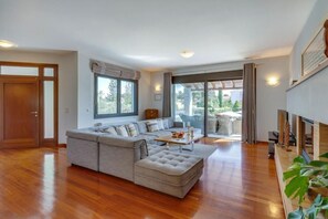 Un salón amplio con un sofá seccional gris grande, una mesa de centro y un ventanal corredero que da a un balcón.