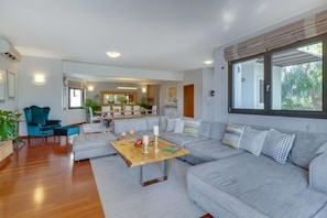 A modern living room with a grey sofa, wooden coffee table, and teal armchairs. - Villa Ampelaki (Chania)