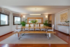 Un comedor con una larga mesa de madera, sillas blancas y un arreglo floral central.