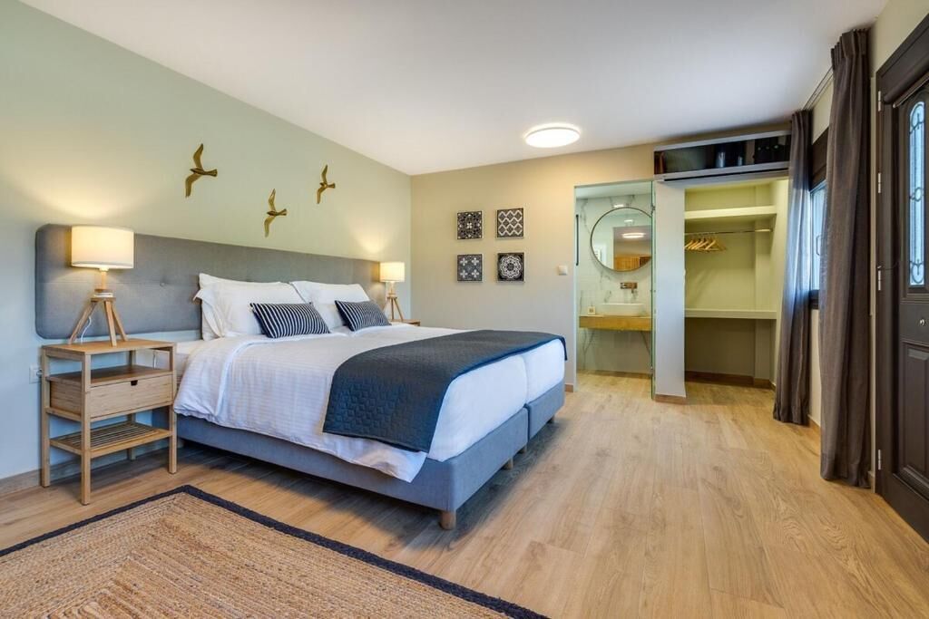 A bedroom with a bed, bedside tables, a mirror, a wardrobe, and a small bathroom.