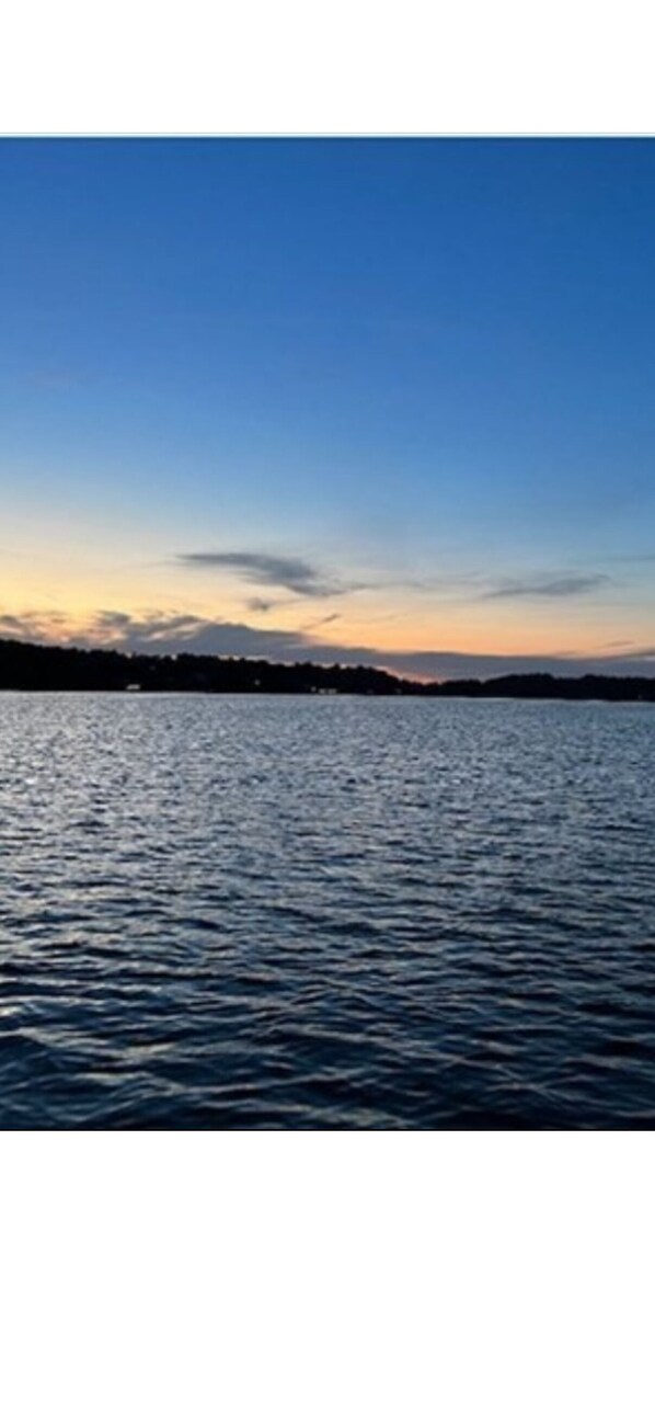 Une étendue d’eau calme, sous un ciel dégagé, avec une côte visible au loin.
