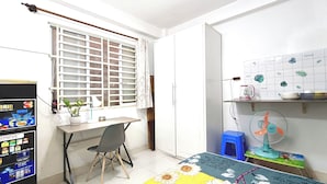 Una habitación con escritorio, silla, armario, radiador, ventilador y una pared con un calendario.
