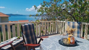 A terrace with a table set for two, overlooking a body of water and a distant mountain range. - Apartments Mia with new whirlpool from 2026 and 7 minutes walk from the beach (Okrug Gornji)