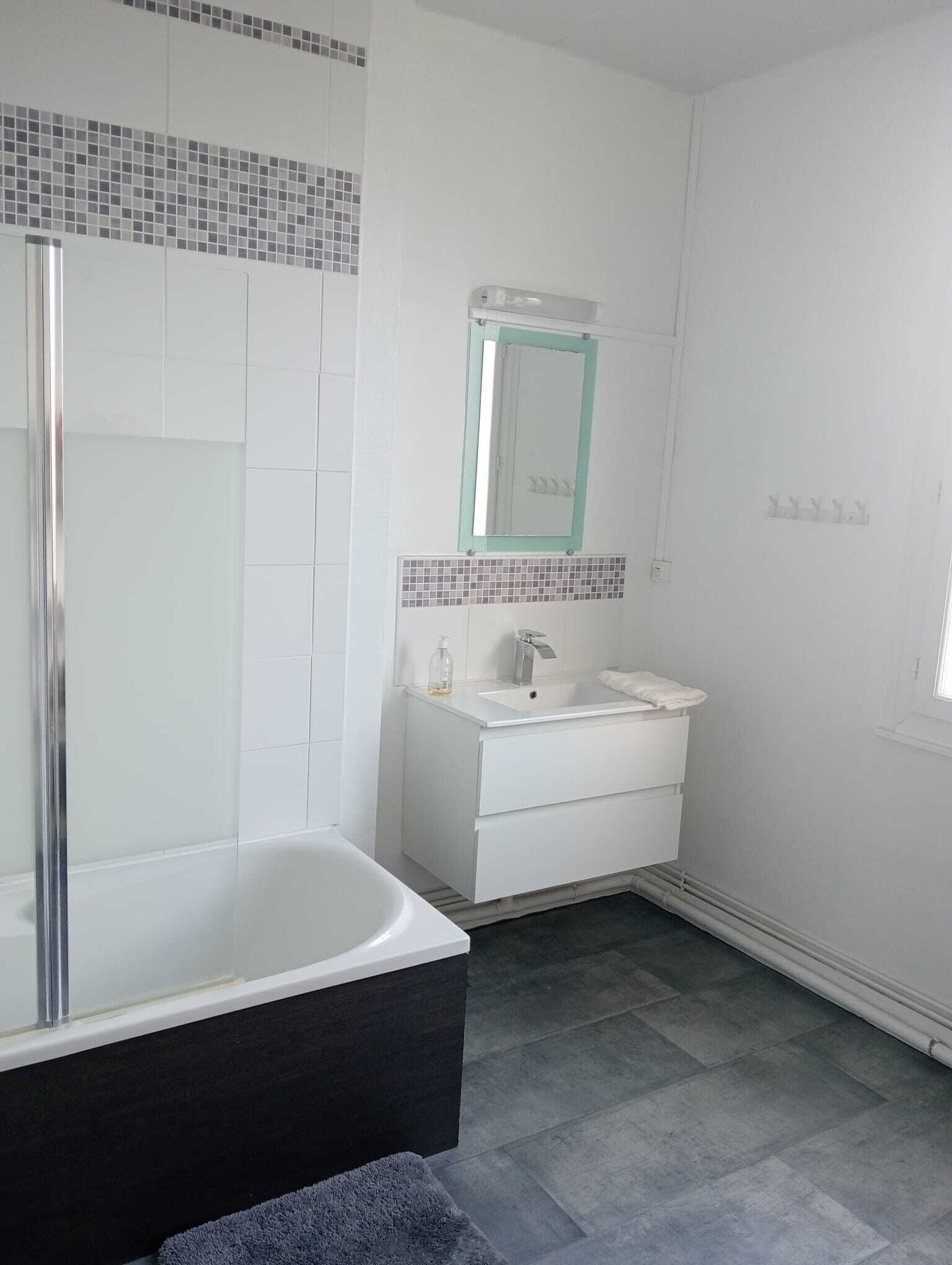 Un baño con bañera, lavamanos y espejo.