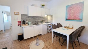 Une cuisine de taille réduite avec des meubles blancs, un évier et un coin repas comprenant une table et des chaises.