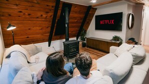Ein Wohnzimmer mit Kamin, Wand-Fernseher und einer Couch.