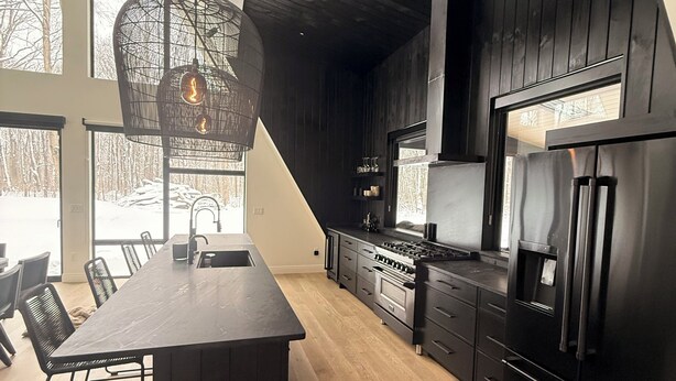 Una cocina moderna con una isla grande, armarios oscuros y vistas al exterior.