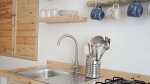 A kitchen with a stainless steel sink, wooden cabinets, a gas stove, and a utensil holder. - Poésia – Portuligno Apartment 50 mt from the most beautiful beaches in Salento! (melendugno)
