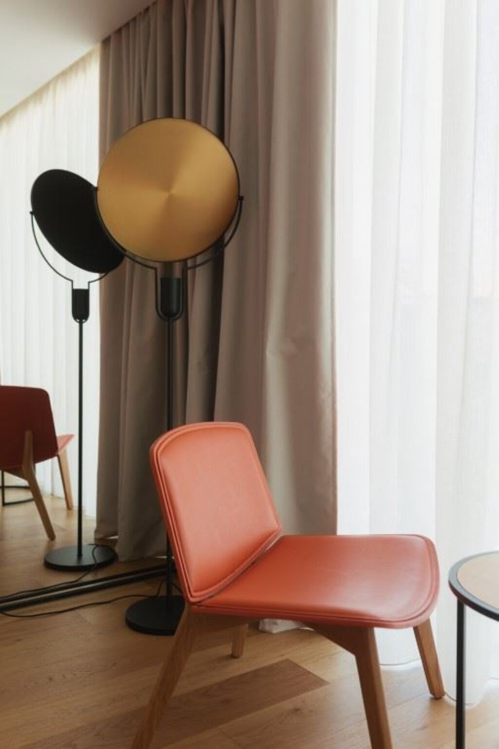 Ein Zimmer mit einem modernen Sessel, einer Stehlampe und einem Tisch.