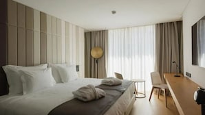 Ein modernes Hotelzimmer mit einem großen Bett, einem Schreibtisch und einem Stuhl.