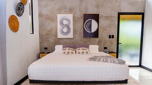A modern bedroom with a large bed, a neutral color palette, and artwork on the walls.
