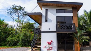 A modern two-story building with a balcony, large windows, and a staircase leading to the upper level.