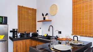 A compact kitchen with a microwave, coffee maker, and wooden blinds.