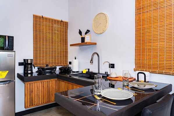 A compact kitchen with a microwave, coffee maker, and wooden blinds. - Rio Grande (Bahia Ballena)