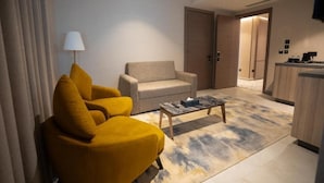 Ein modernes Hotelzimmer mit Sofa, Sessel, Couchtisch und Lampe.