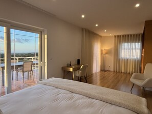 Habitación de hotel con una cama grande, un escritorio, una silla y vistas al exterior.