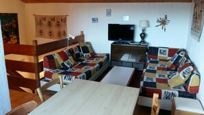 En hyggelig stue med sofa, træbord, fjernsyn og lampe.