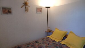 Et soveværelse med seng, to puder, et natbord, en lampe og vægdekorationer.