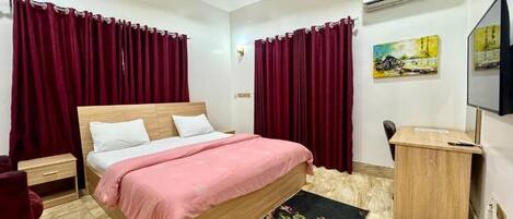 Une chambre à coucher avec un lit en bois, des rideaux rouges, un bureau et un téléviseur.