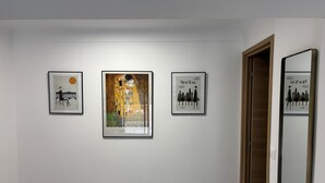 En billedvæg med tre indrammede kunstværker, der viser Paris, New York og Gustav Klimts 'Kysset'.