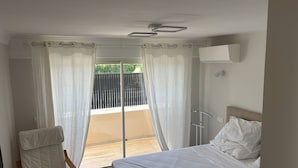 Et hotelværelse med seng, stol, vindue med gardiner og udsigt ud.
