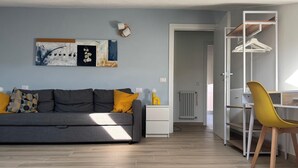 Een moderne woonkamer met een grijze bank, gele kussens, een witte bijzettafel en een gele stoel.