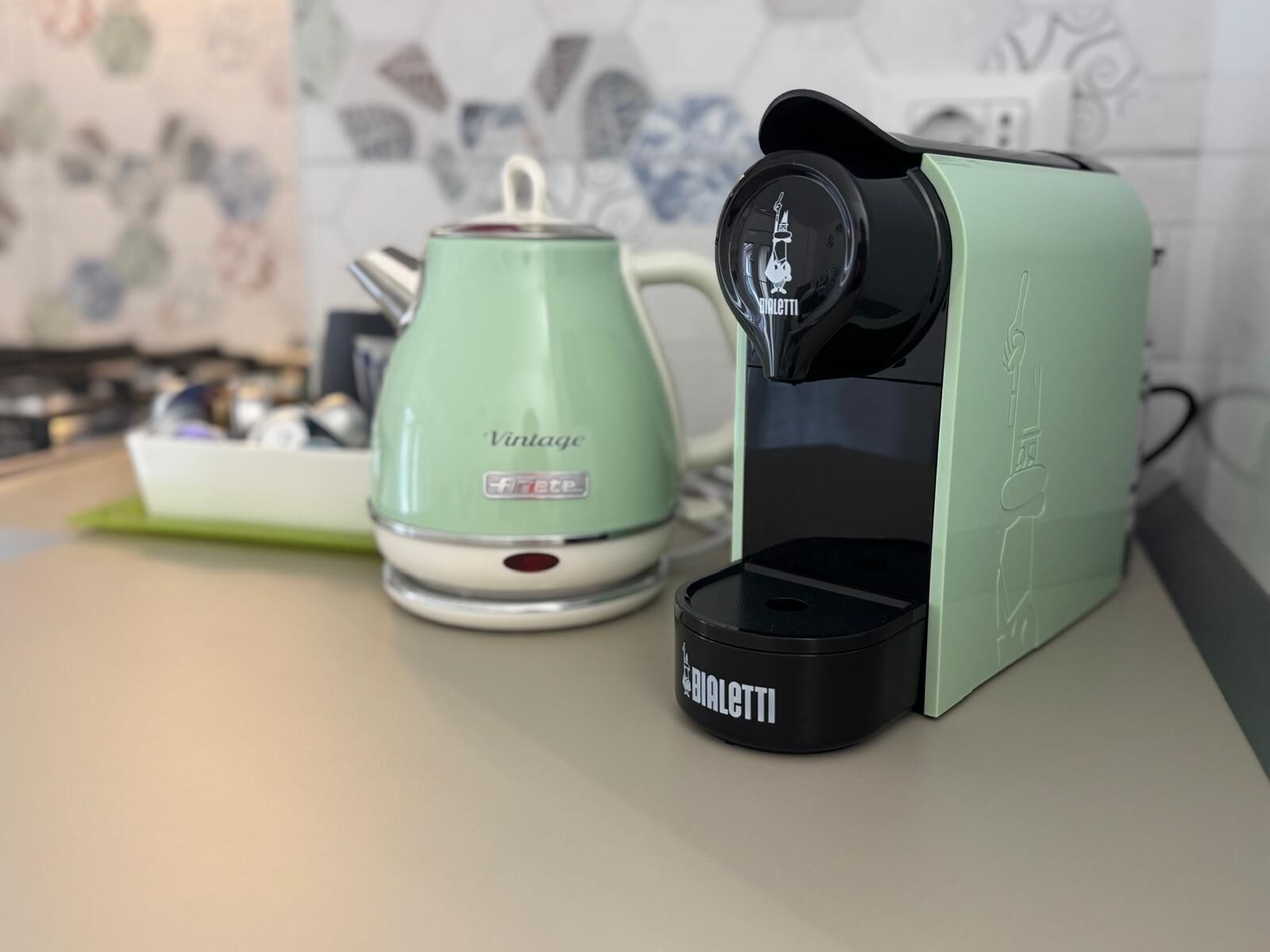 A kitchen with a vintage-style green kettle and a modern coffee maker.