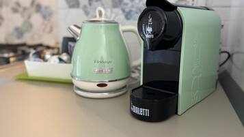 A kitchen with a vintage-style green kettle and a modern coffee maker.