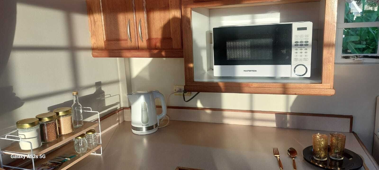 Une cuisine équipée d’un four à micro-ondes, d’une bouilloire et d’une étagère avec des bocaux.