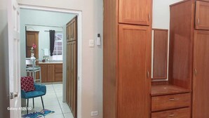 Ein Zimmer mit Holzschränken, einem blauen Sessel und einem kleinen Tisch mit einer Vase.