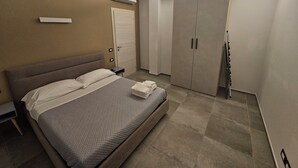 Ein Hotelzimmer mit Bett, Kleiderschrank, Nachttisch und Wand-Klimaanlage.