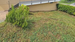 Ein zweistöckiges Gebäude mit Balkon, Ziegeldach und kleinem Garten.