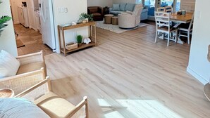 A spacious living area with a wooden floor, a dining table with chairs, a sofa, and a ceiling fan. - Shar’s Cottage - Close to Beach - Bradenton (Bradenton)
