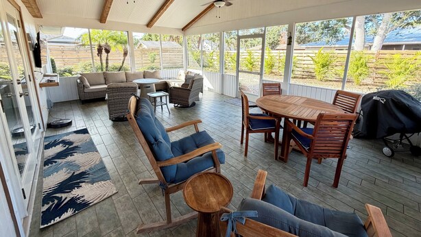 A covered outdoor patio with a dining area, seating, and ceiling fans. - Shar’s Cottage - Close to Beach - Bradenton (Bradenton)