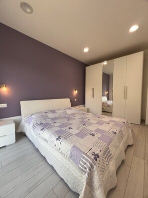 A bedroom with a large bed, a nightstand, a wardrobe, and two wall-mounted lights. - Wonderful two steps from the sea surrounded by greenery, reserved parking space. (Porto Ottiolu)