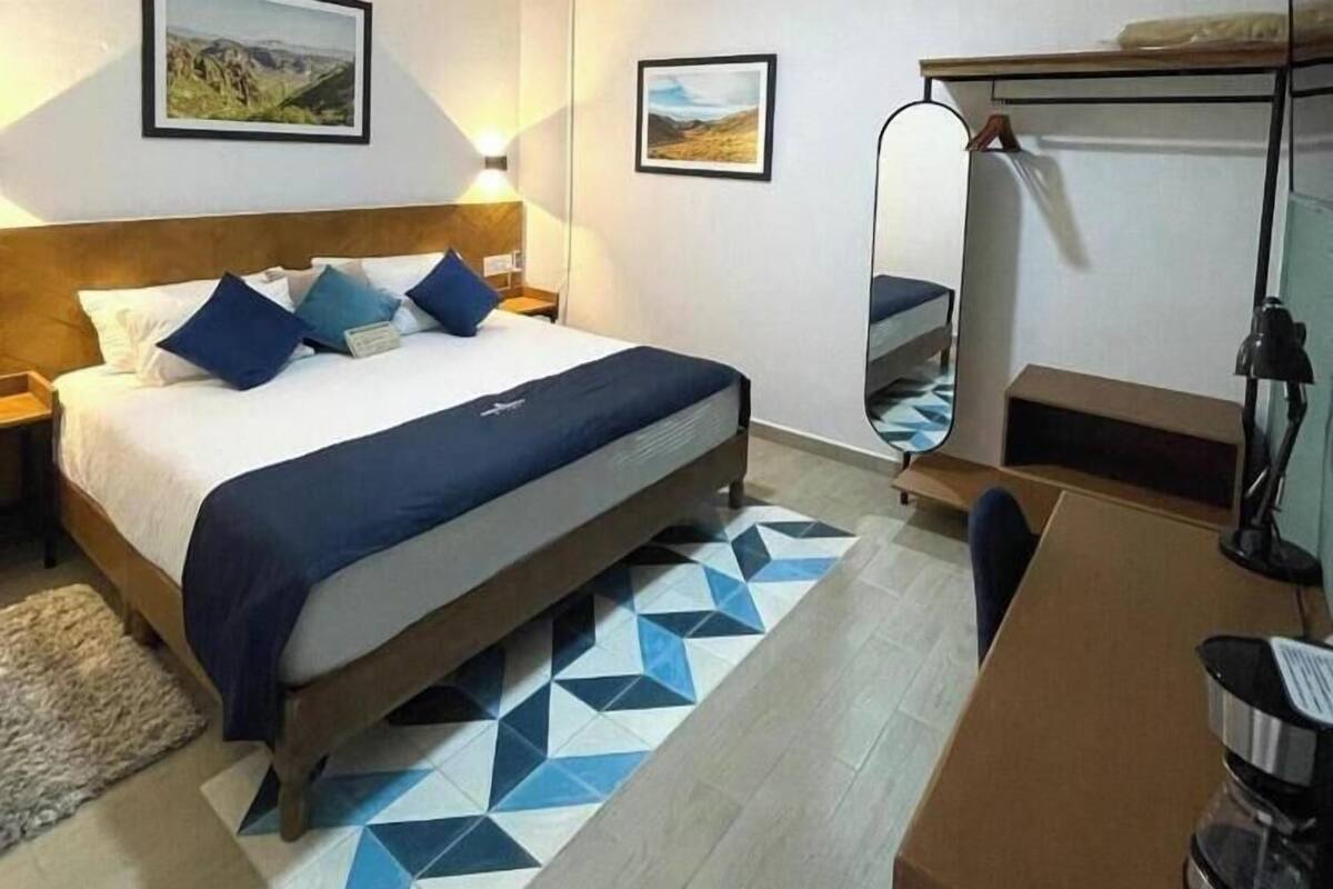 Ein Hotelzimmer mit Bett, Schreibtisch, Stuhl, Kaffeemaschine und Spiegel.