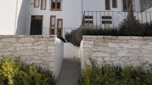 Un edificio moderno de dos pisos con fachada blanca, muros de piedra y un cielo azul claro.