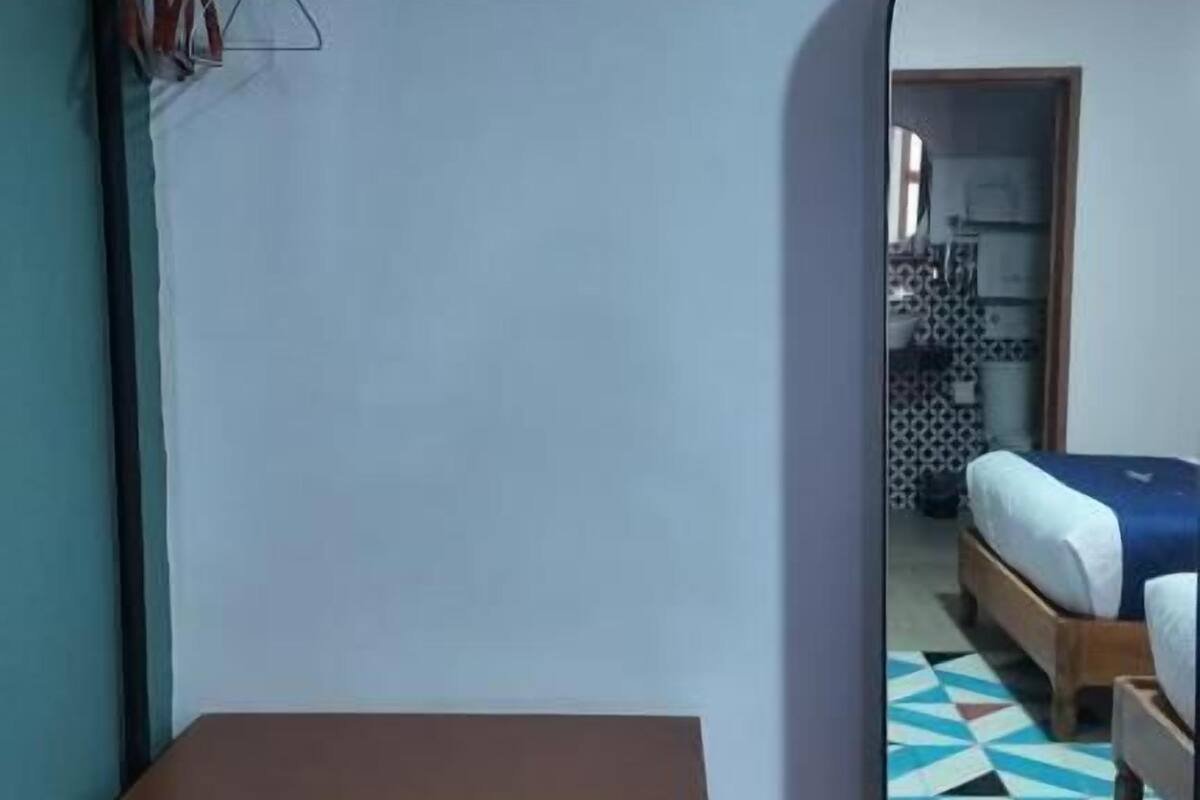 Ein Schlafzimmer mit einem Bett, einem Holzschrank, einem Spiegel und einem Fenster.