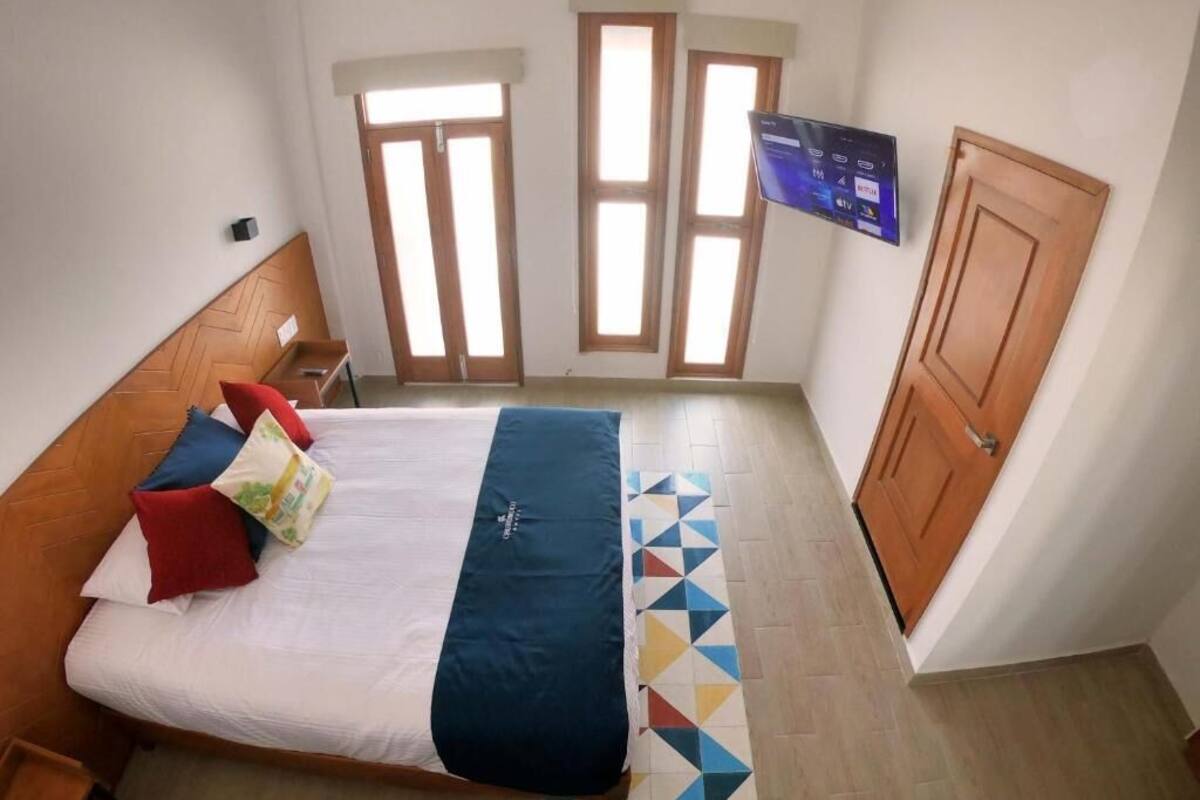 Ein Schlafzimmer mit einem Bett, einem an der Wand befestigten Fernseher und einer Tür.