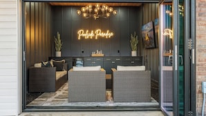 Ein modernes Interieur mit einem Neon-Schild mit dem Schriftzug "Poolside Paradise", Korbmöbeln und einer Glastür.