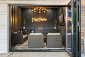 Un interior moderno con un letrero de neón que dice 'Poolside Paradise', muebles de mimbre y una puerta de cristal de entrada.