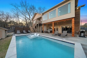 Ein modernes, zweistöckiges Haus mit Swimmingpool, Sitzgelegenheiten im Freien und einer Grillzone.