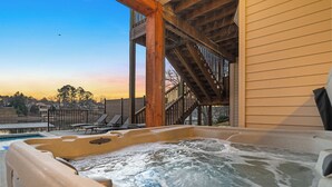 Ein Whirlpool mit Holzterrasse und Blick auf eine Wohngegend bei Sonnenuntergang.
