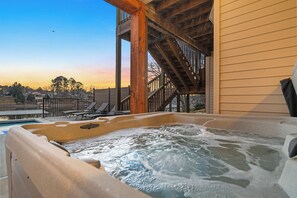 Un jacuzzi con muelle de madera y vista a una zona residencial al atardecer.