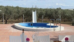 An outdoor pool area with a tiled patio, a table set for breakfast, and a vineyard in the background. - Casa las Cordobesas is a charming rural lodging in the middle of nature. (La Guijarrosa (Córdoba))