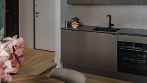 Eine moderne Küche mit einem Holzesstisch, einem Blumentopf und einem eingebauten Backofen.