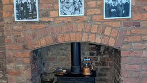 A brick fireplace with a black stove and three black-and-white photographs of a band on the wall above. - Coach house cottage by sefton park, built in 1850.  Entire house ! (Liverpool)